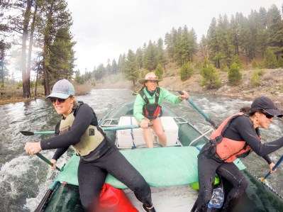 Strong, independent women on a rafting trip rowing in big rapids. Friends in their 40s rafting the Truckee River.