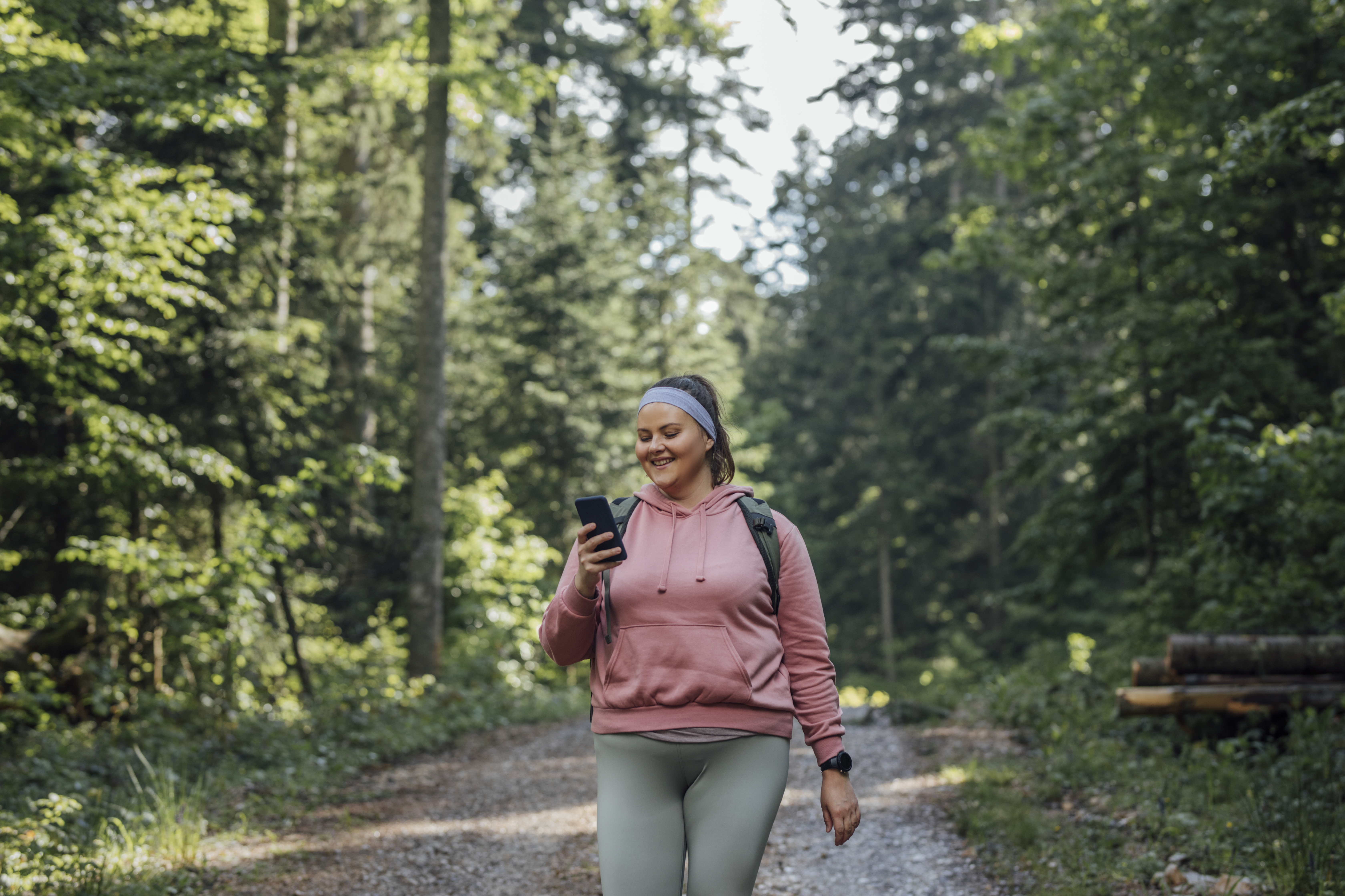 Back to nature: a happy young Plus Size woman spending the day outdoors and taking photos with her smart phone.