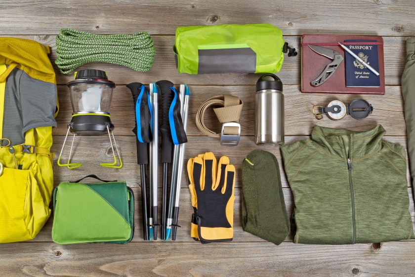 High angled view of organized hiking gear placed on rustic wooden boards in rectangle format.