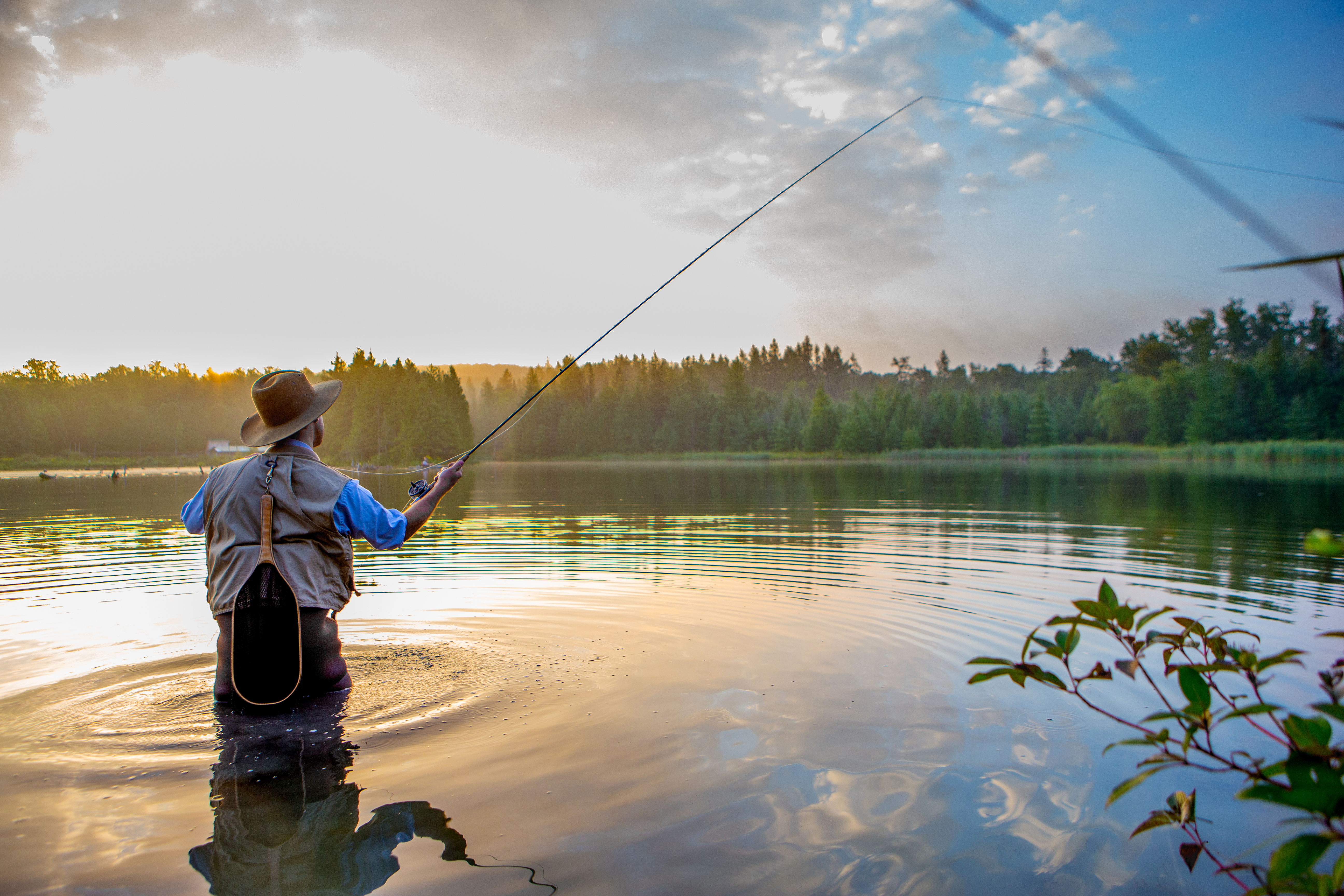 Young man flyfishing at sunriseYoung man makes a cast with his fly rod while flyfishing at sunrise.