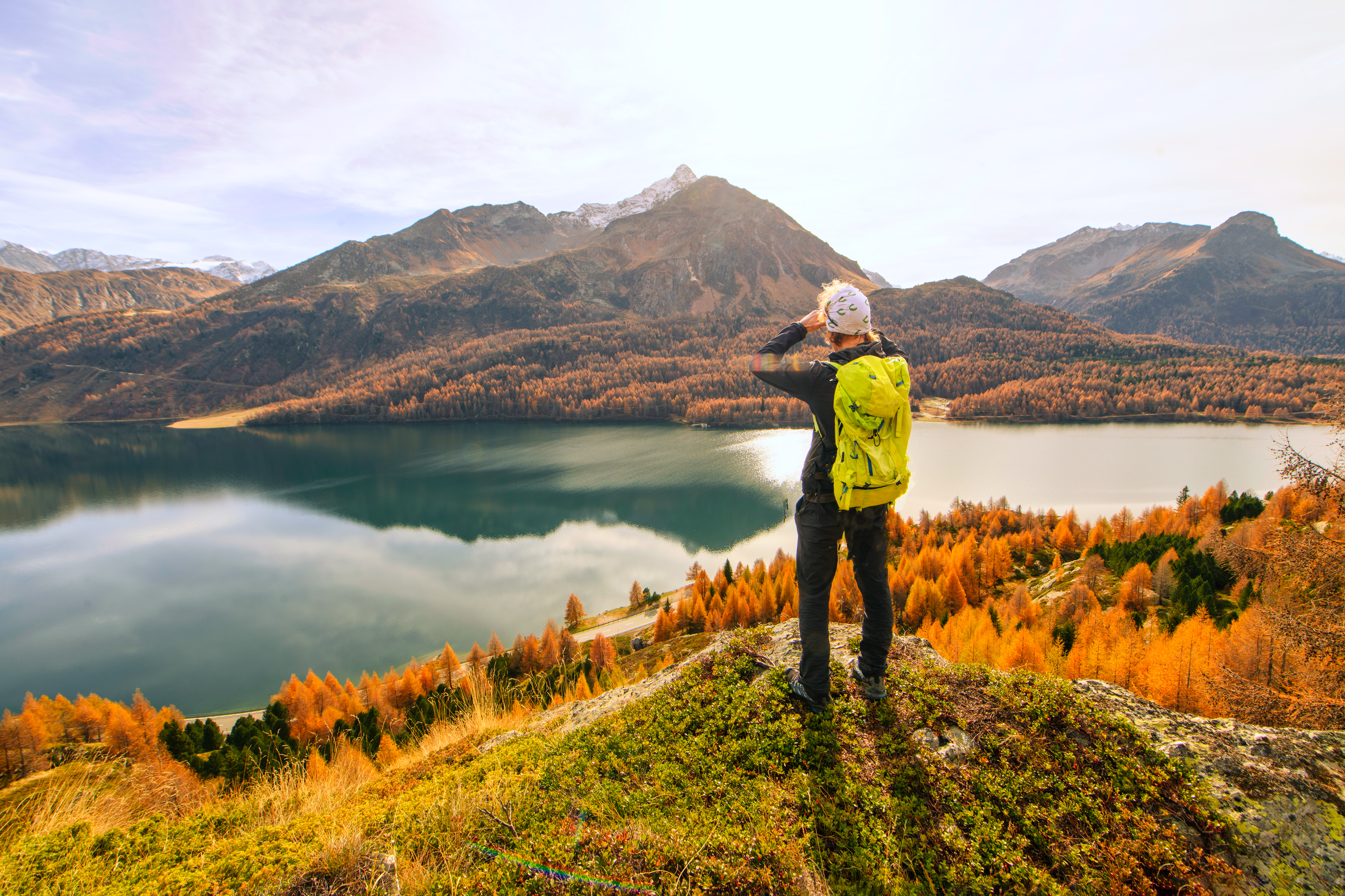 Man stands at mountain lake in fall autumn landscape