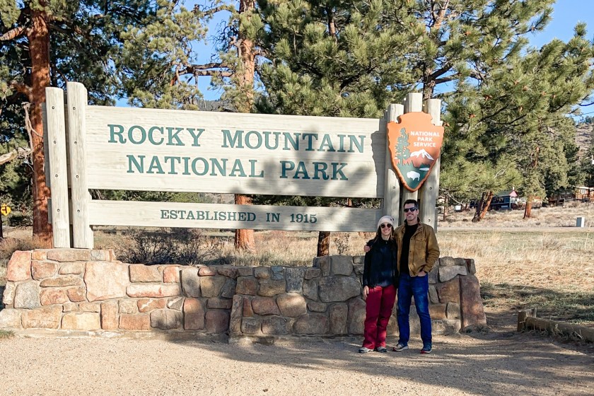 Author and companion standing in front of Rocky Mountain National Park sign 