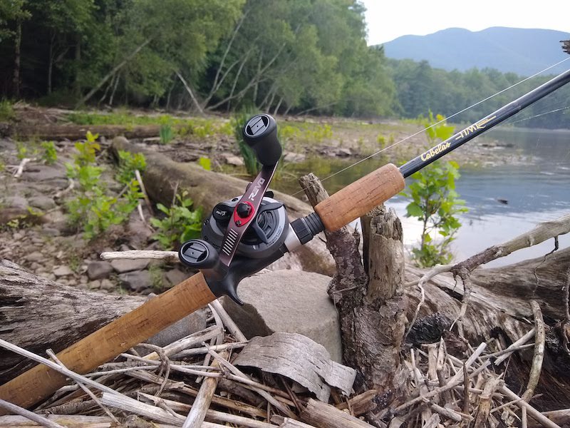 The Revo Reel on a pile of sticks in front of a body of water