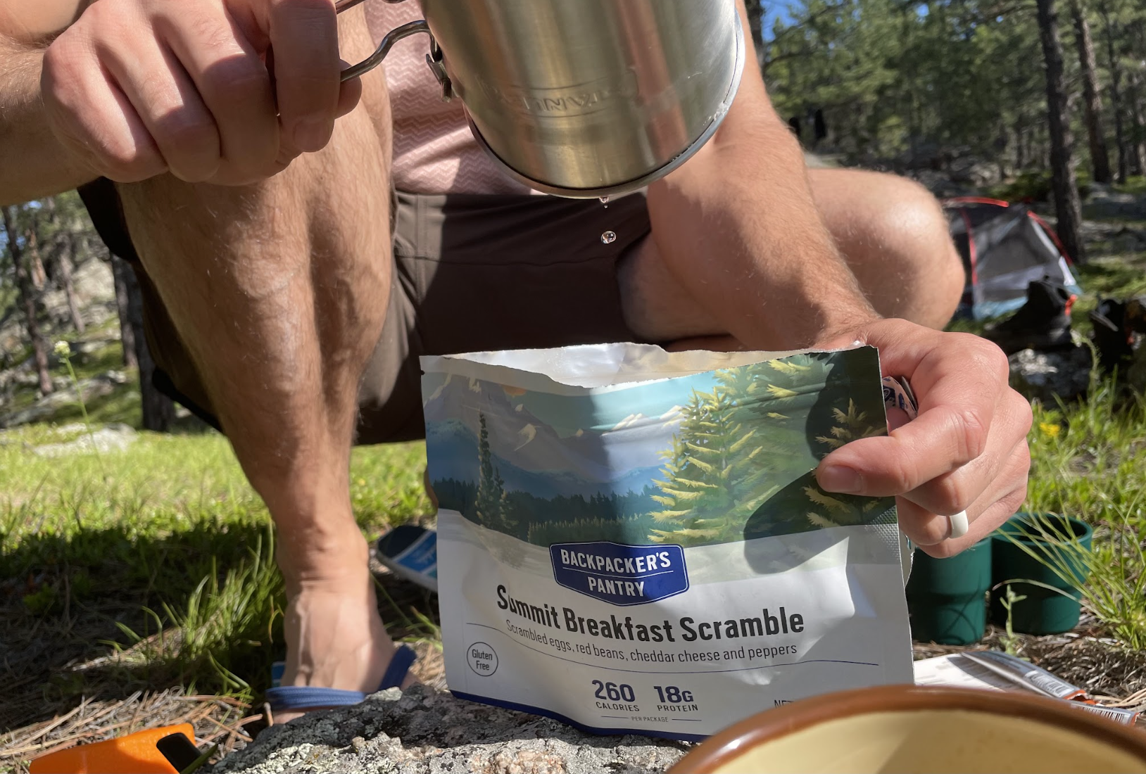 A hiker crouched on the ground, preparing the Hiker's Breakfast Scramble