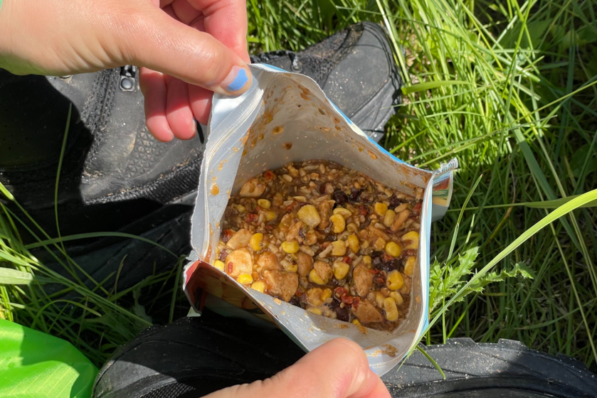 An opened package of Backpacker's Pantry Rice and Beans over a patch of grass