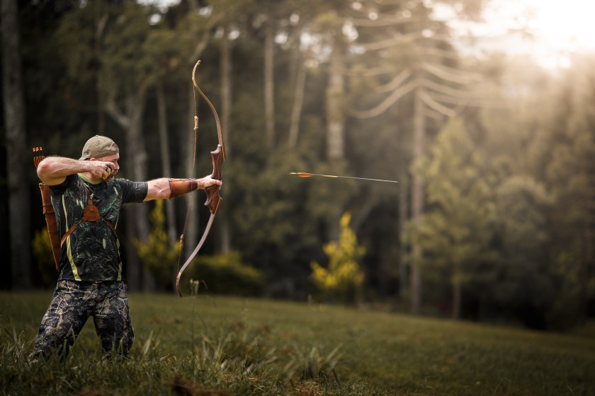 Strong archer firing arrow on nature.