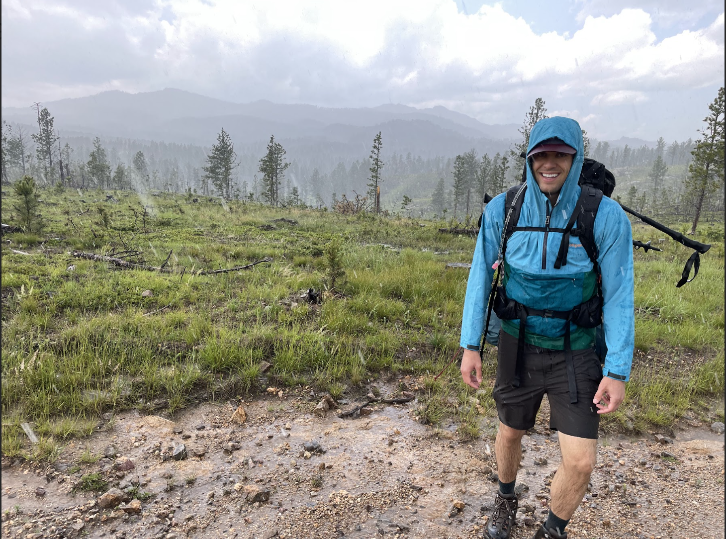 A hiker wearing a blue rainjacket while on a trail