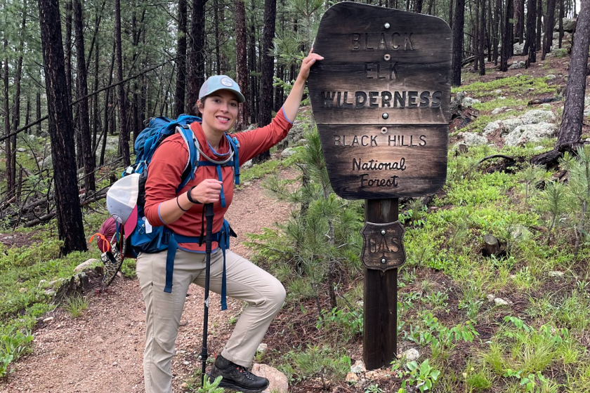 Hiker wearing a red rainjacket and khaki rain pants while on a hiking trail