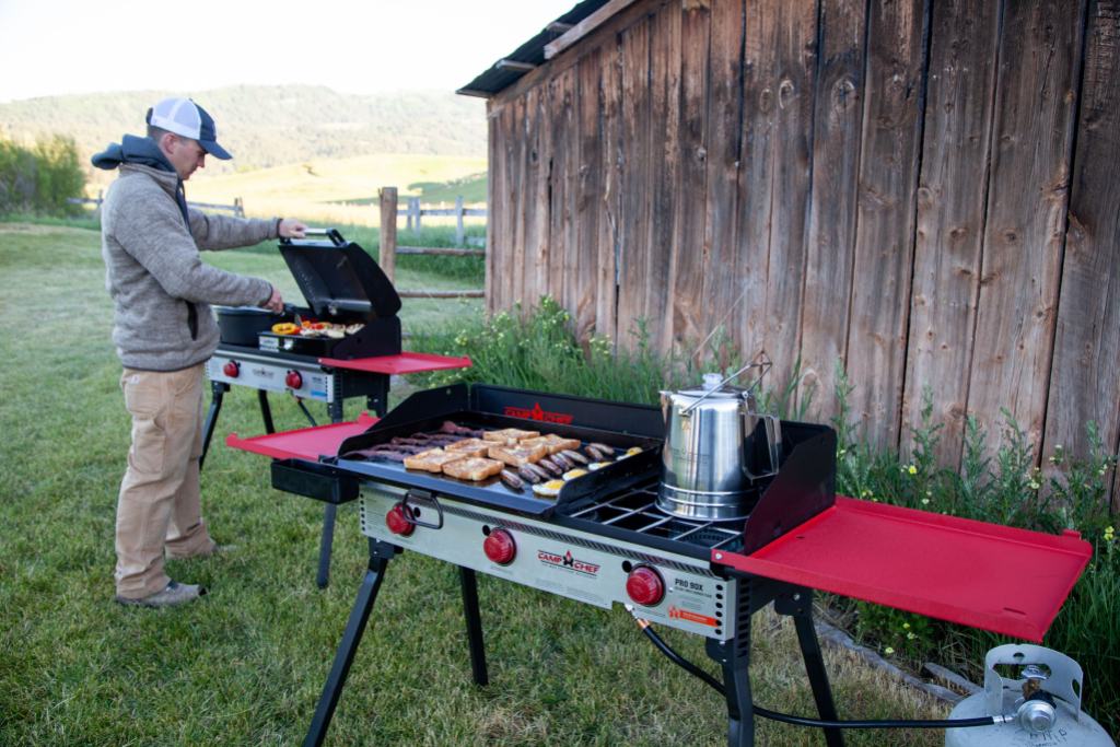 Person using a red and black Camp Chef grill 