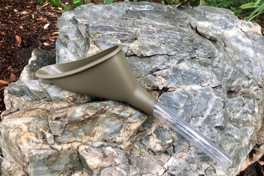 A forest green pee funnel resting on a rock 
