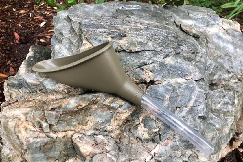 A forest green pee funnel resting on a rock