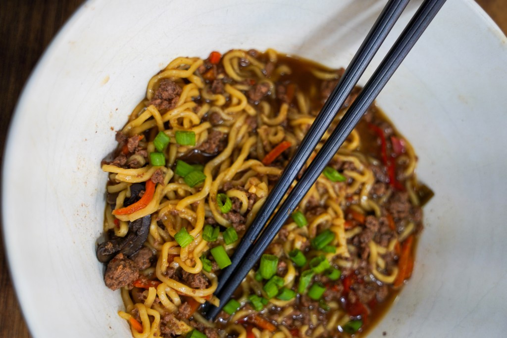 Crock pot venison ramen, served in a bown with chop sticks. 