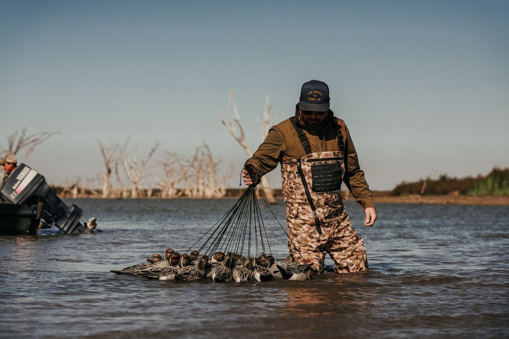 Person standing in a body of water holding a duck wader