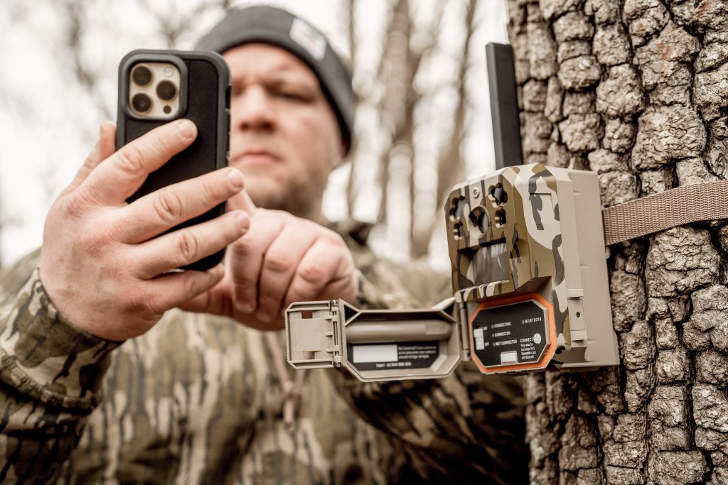 Person coordinating their phone with an Edge Pro Lifestyle that is tied to a tree