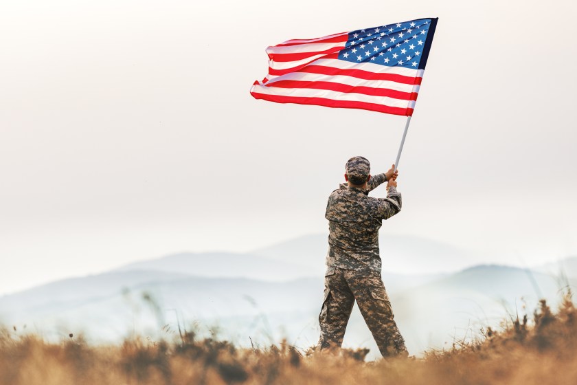A veteran waving an American flag in the outdoors.