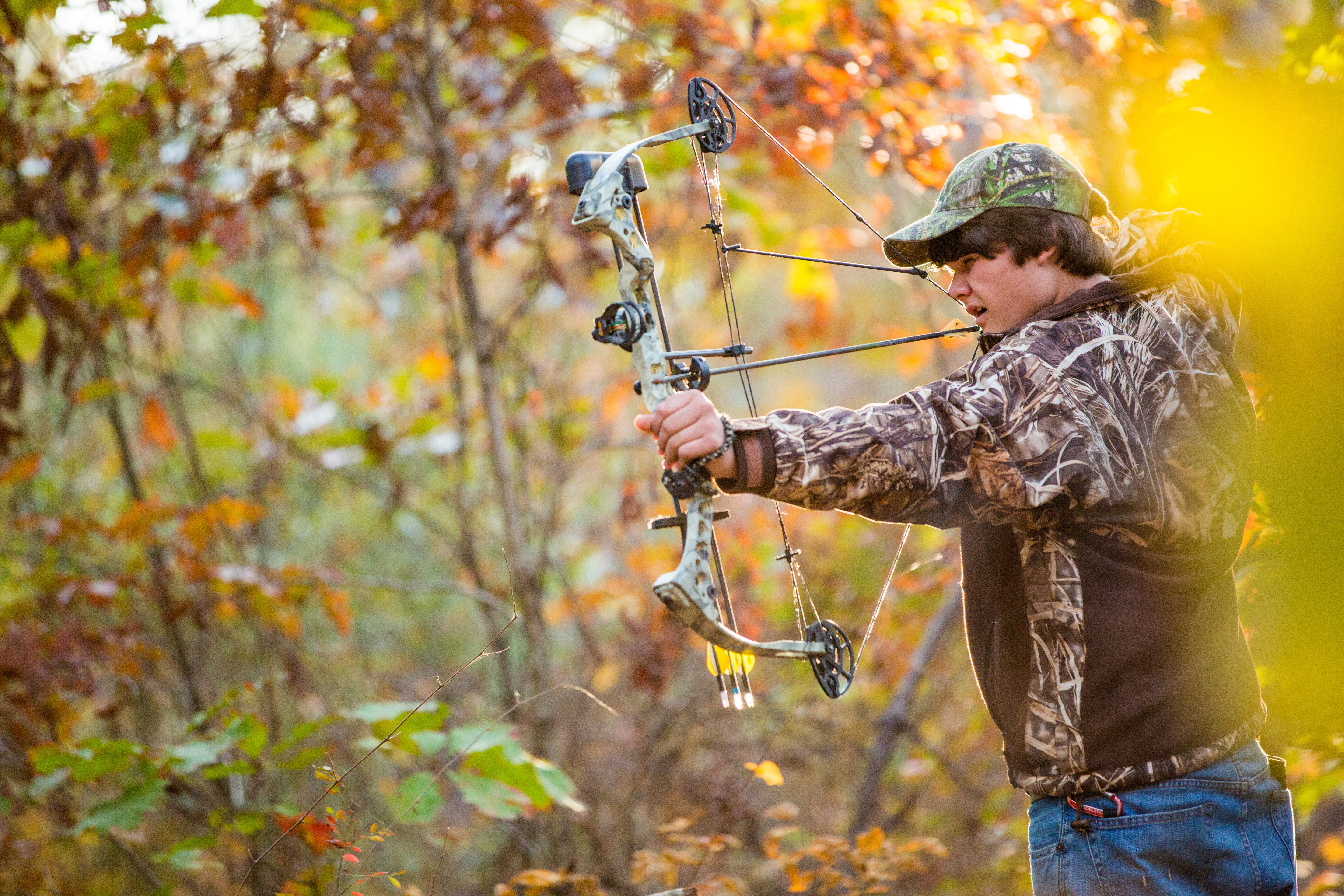 southern american teen boy out in the woods bow hunting for deer