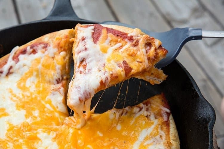 Pizza in a cast iron skillet over a wooden table