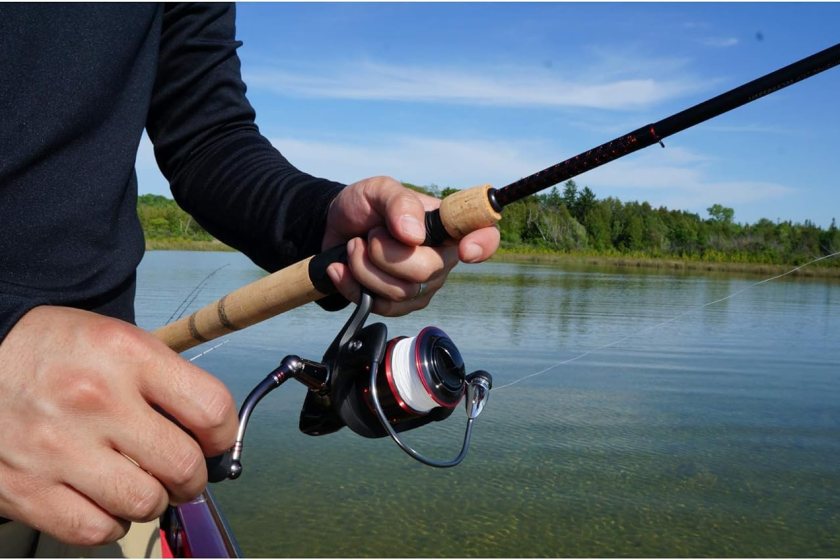 A person holding a black and wooden Ugly Stik Fishing Rod