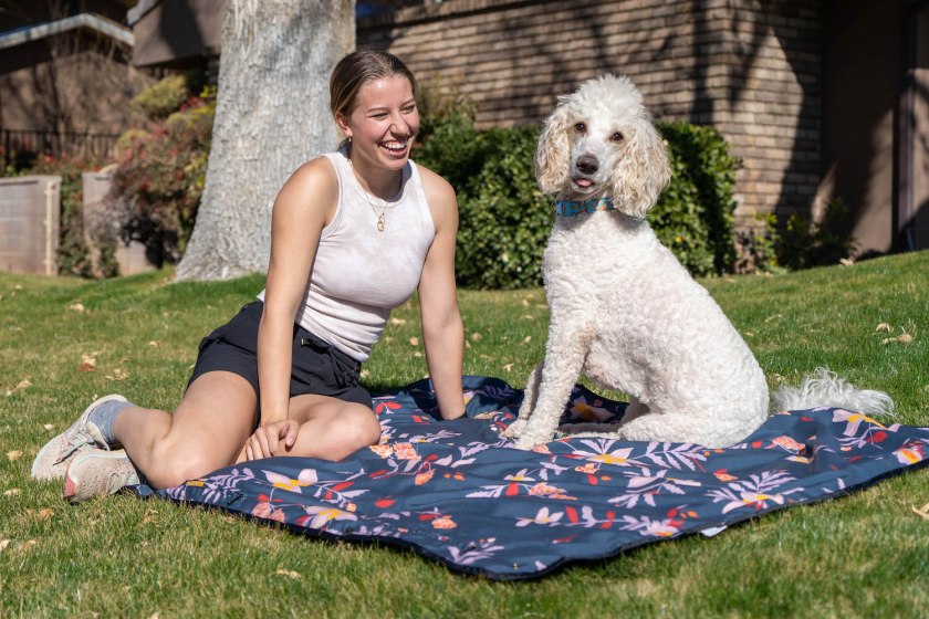 Person and dog sitting on a blue Coalatree Blanket