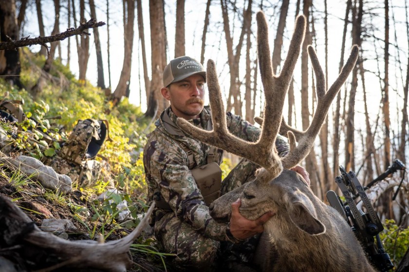 A hunter wearing Kryptec apparel while holding a deer