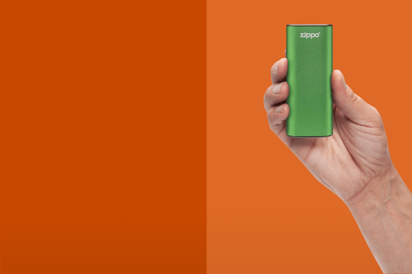 Hand holding a green lighter on an orange background