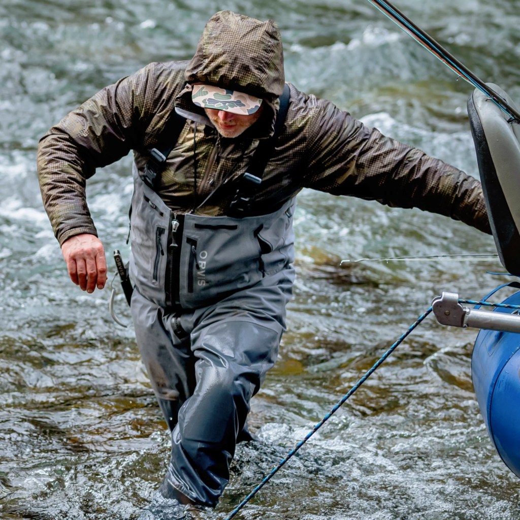 Person wading in a body of water while wearing Orvis waders 