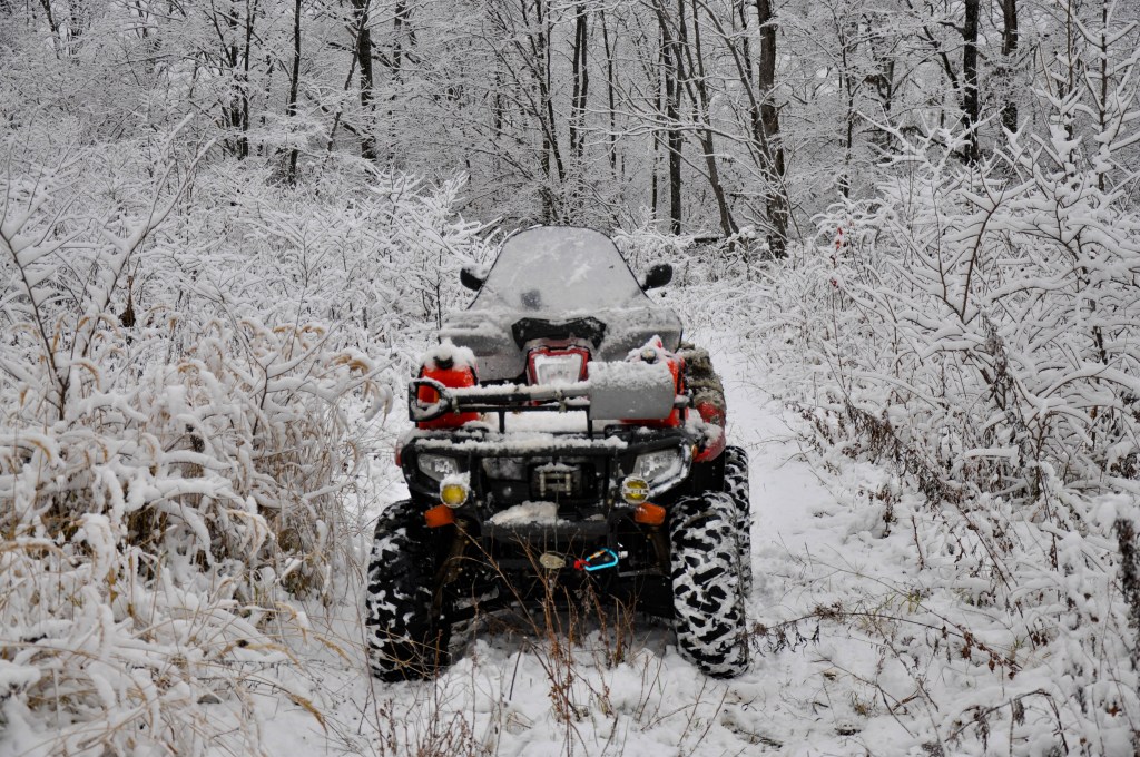 An ATV on wheels stands on a forest road among snow-covered bushes. Winter. Travels in the Khabarovsk Territory of the Russian Far East