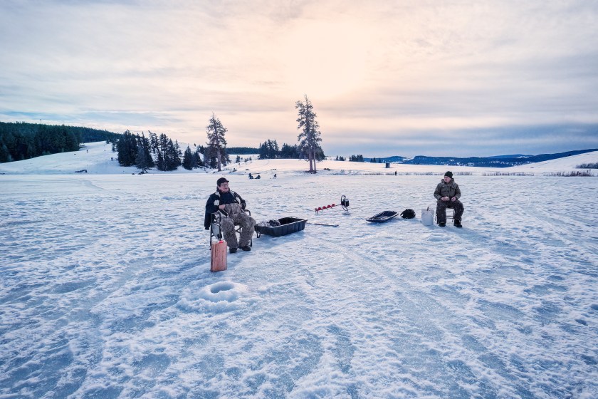 First Nations and Caucasian men in 60s and 70s ice fishing for rainbow trout at Marquart Lake, Merritt, British Columbia, Canada.