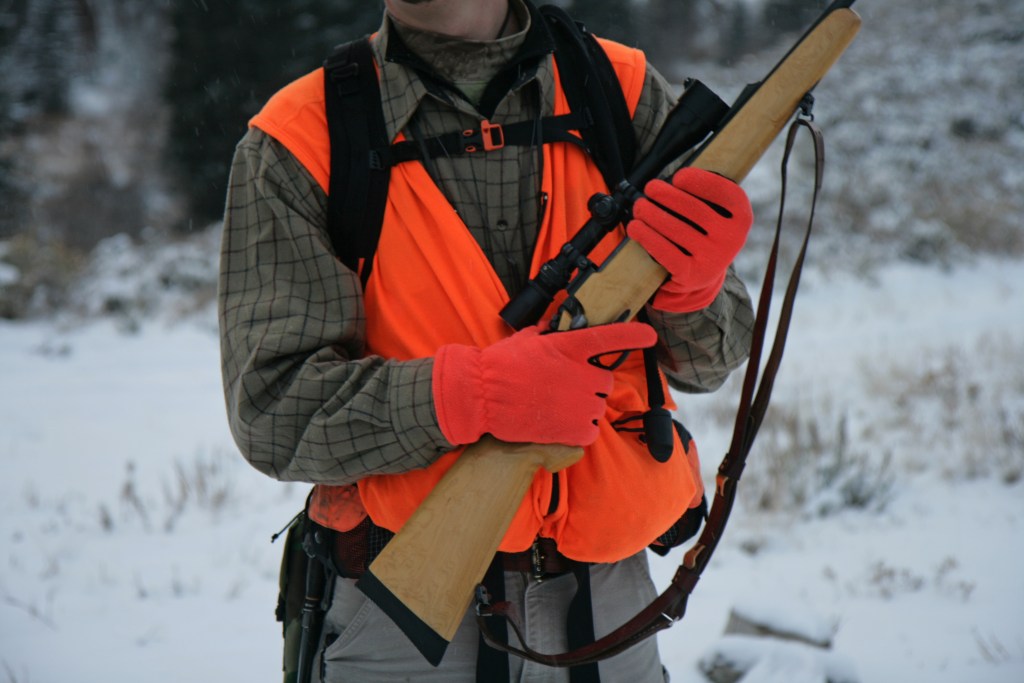 Close up of hunter dressed in day light orange holding rifle.