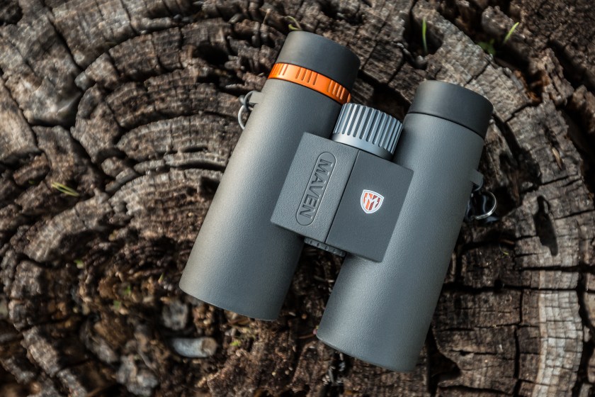 A pair of gray binoculars on a wooden tree stump