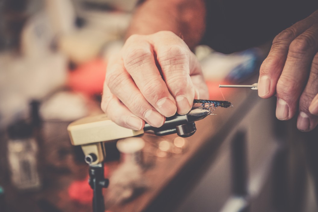 Close up image of a person tying fishing flies in a vice.