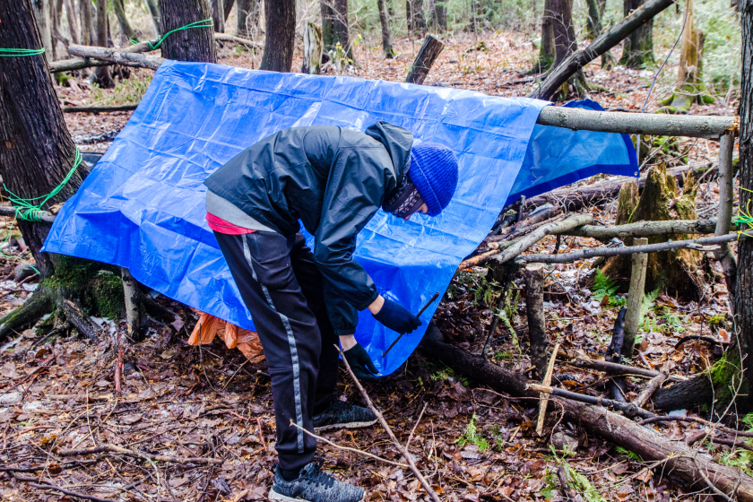man building a shelter in the woods